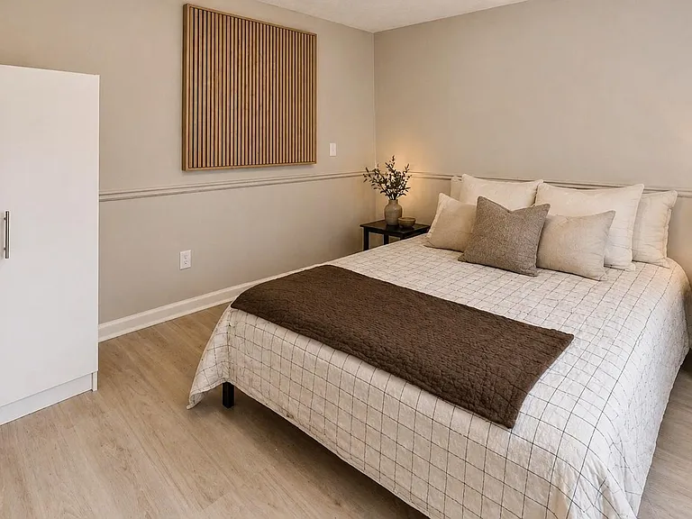 Furnished bedroom with a full/queen bed, nightstands with lighting, and a wardrobe for convenient in-room storage.