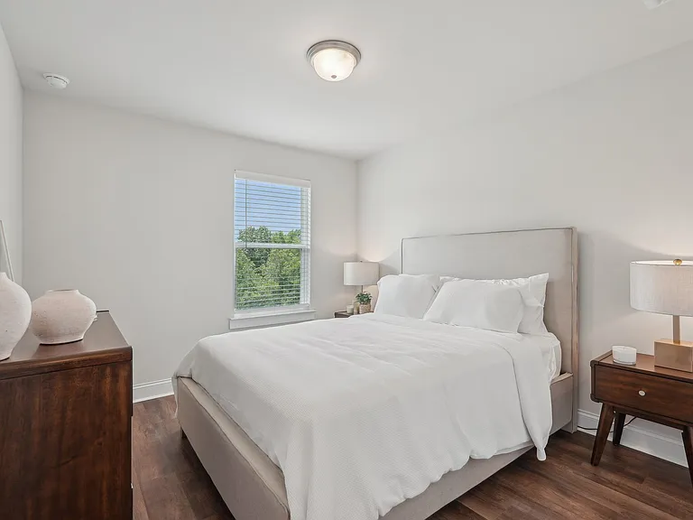 Secondary bedroom with a queen-size bed and bright natural light streaming through a large window.