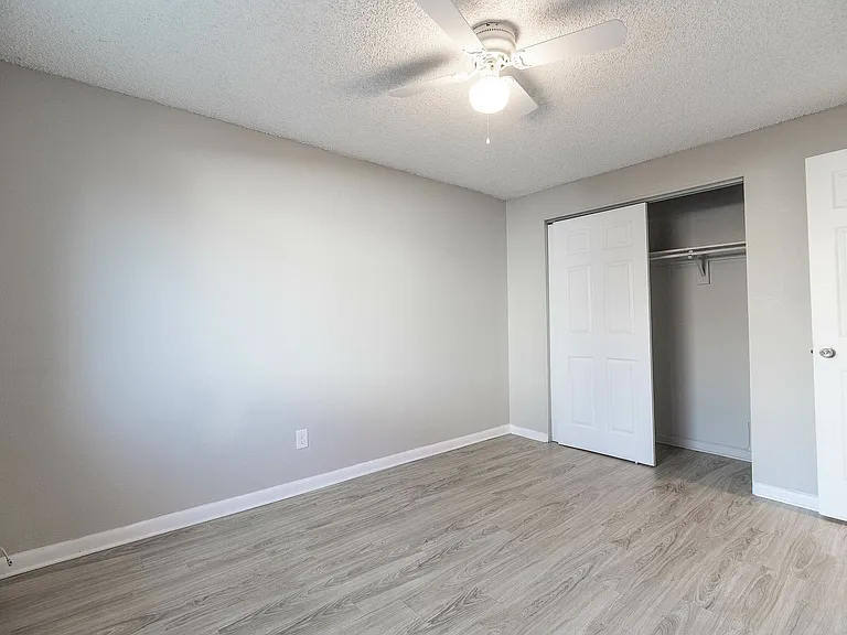 Bright and airy bedroom with sleek wooden floors and a spacious closet, perfect for a modern living setup.