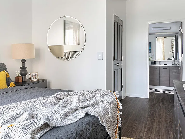 Spacious apartment bedroom with wood floors and bathroom.
