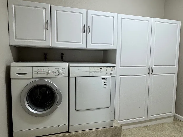 Elevated washer and dryer, dedicated folding station, and abundant storage - a highly functional, well-designed laundry room.