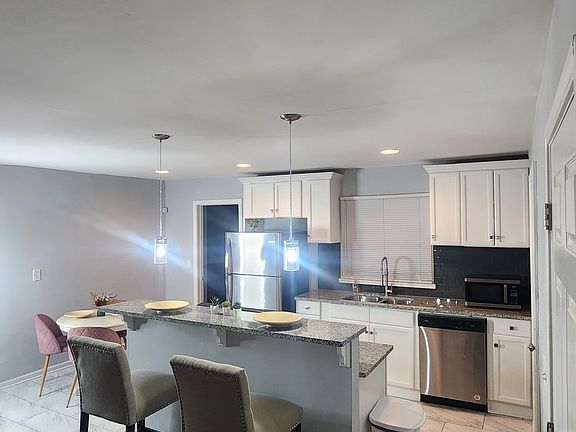 Modern kitchen with stainless steel appliances, granite counters, and pendant lighting. Table seating and open layout make it perfect for cooking, dining, and entertaining.