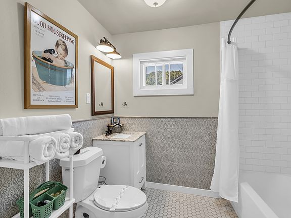 Tub/shower combo, newly tiled bathroom accessible from front bedroom and also a kitchen entrance for guest use. Access to full size stacked washer and dryer is in this room as well.