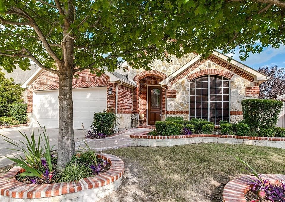 View of the front of the home with stone planters and Austin Stone elevation.