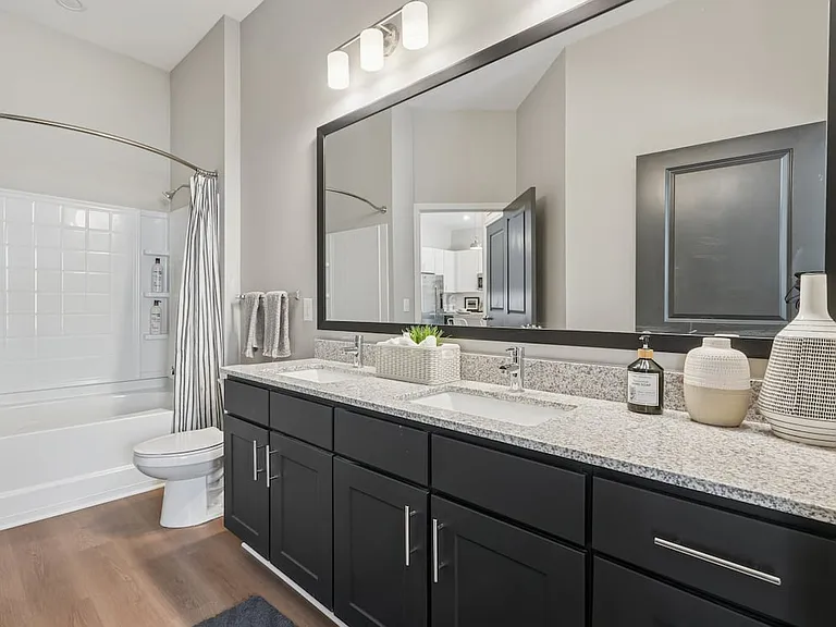Bath with dark cabinetry, speckled granite countertops, and hard surface flooring