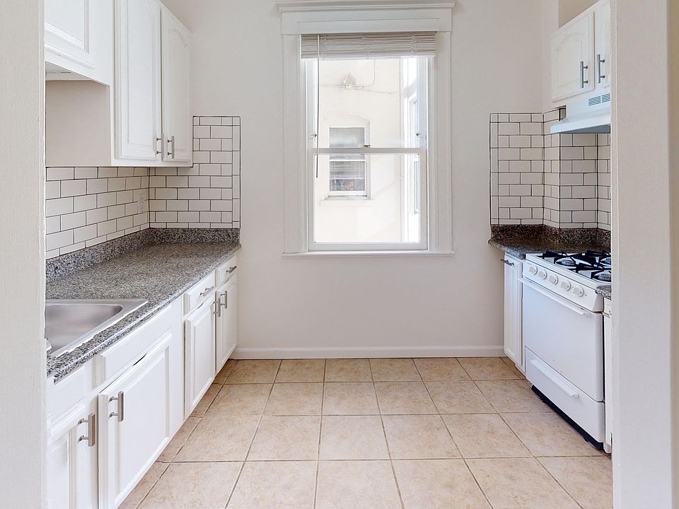 Kitchen with cabinets, stove, range hood, and sink