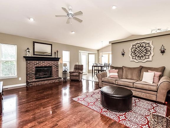 Vaulted great room has new floor, wood burning fireplace, neutral colors and open to kitchen