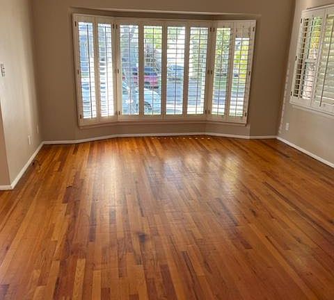 Interior living room with beautiful hardwood floors and plantation-like window shutters.