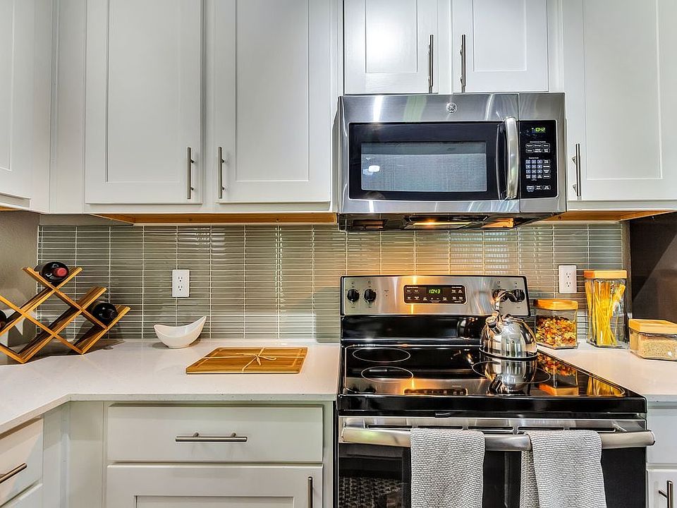 Classic Package II kitchen with stainless steel appliance, white quartz countertop, tile backsplash, white cabinetry, and hard surface flooring