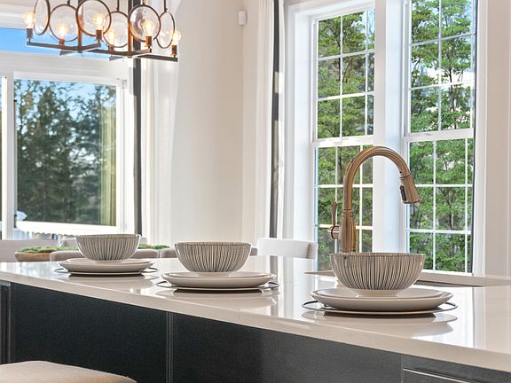 Kitchen with light countertop and dark wood island in a DRB Homes Aspen II model at the Deerfield Pr