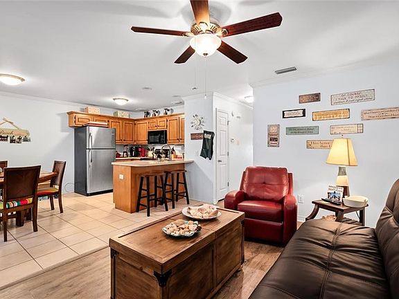 Living room with ceiling fan, ornamental molding, and light tile flooring