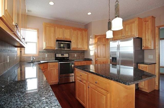 Center Island kitchen with cherry wood floors, maple cabinets, granite counters, tile backsplash, Brand New Stainless Steel Refrigerator and Range, pendant lights, walk-in pantry, 9' ceilings
