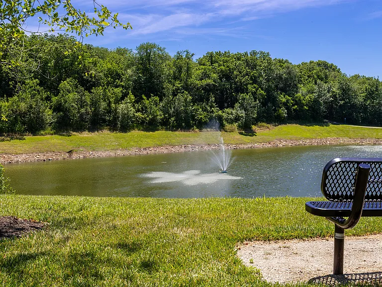 Relax by the serene lake where you can enjoy the soothing sounds of the fountain and the beauty of nature from a comfortable bench.