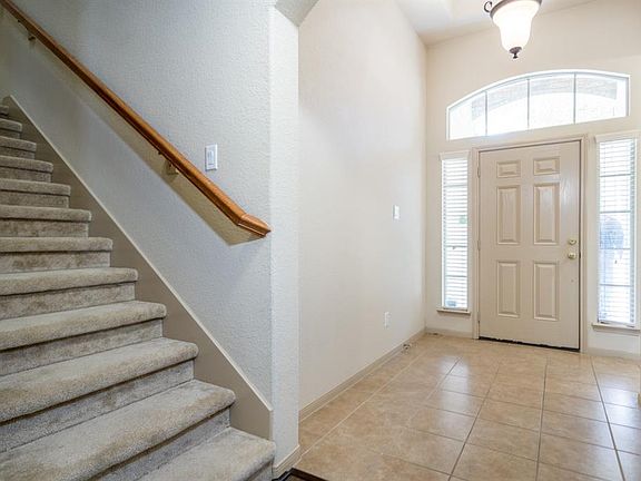 Bright entry with tile floors and high ceiling.