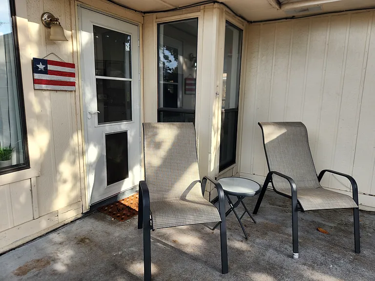 Private back patio with patio furniture and doggie door, fenced backyard for pets.