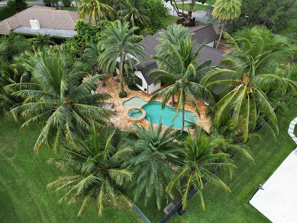 Aerial shot capturing the size of the yard, the pool area, and all the tropical greenery surrounding the home.