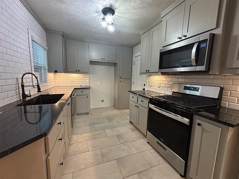 Kitchen featuring a dark sink basin, matte black faucet, and light subway tile backsplash