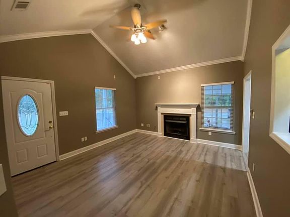 Living room with high vaulted ceiling and gas ventless fireplace. ~350 sqft covered front porch off of this space.