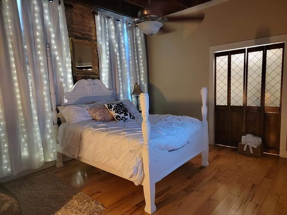 The room has exposed brick walls and original hand sawn beams across the ceiling.