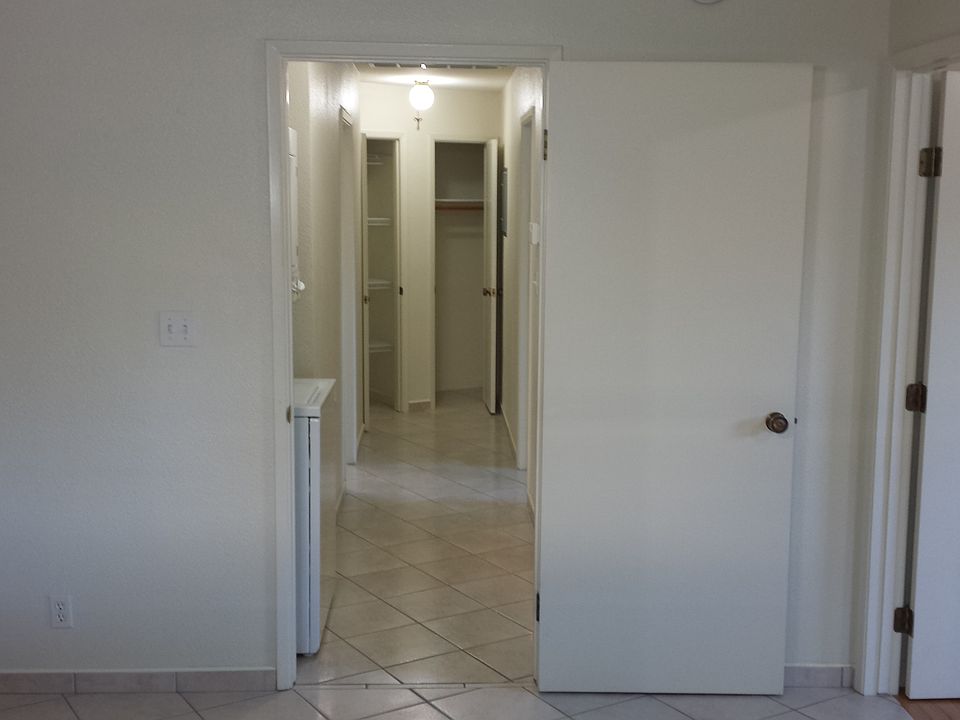 This is looking from the kitchen down the hall where there is a bathroom on the left and a bedroom on the right.