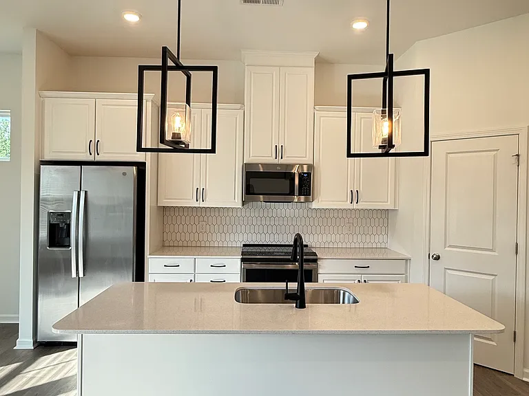 Chef's kitchen featuring quartz countertops, a large center island, stainless steel GE appliances, and designer lighting.