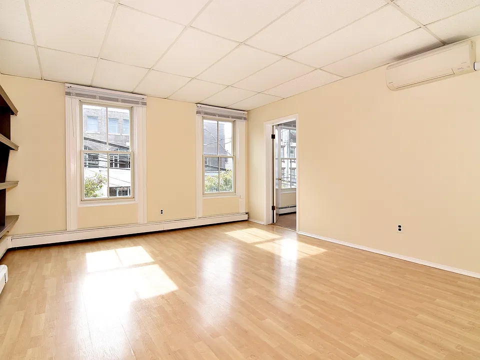 Living room and dining area. Featuring two front facing windows and a mini-split unit.