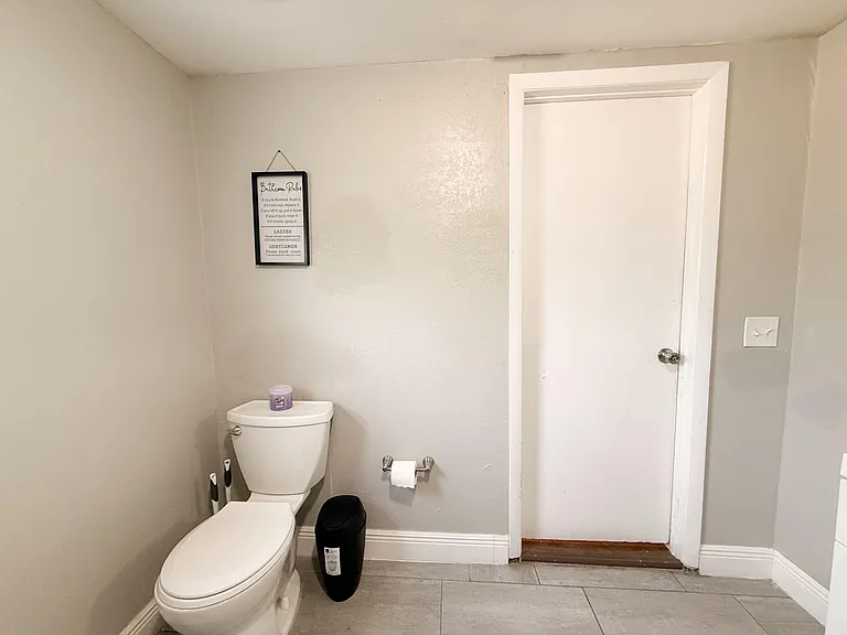 Functional bathroom with tile flooring, neutral walls, and a standard toilet setup with convenient access to storage space.