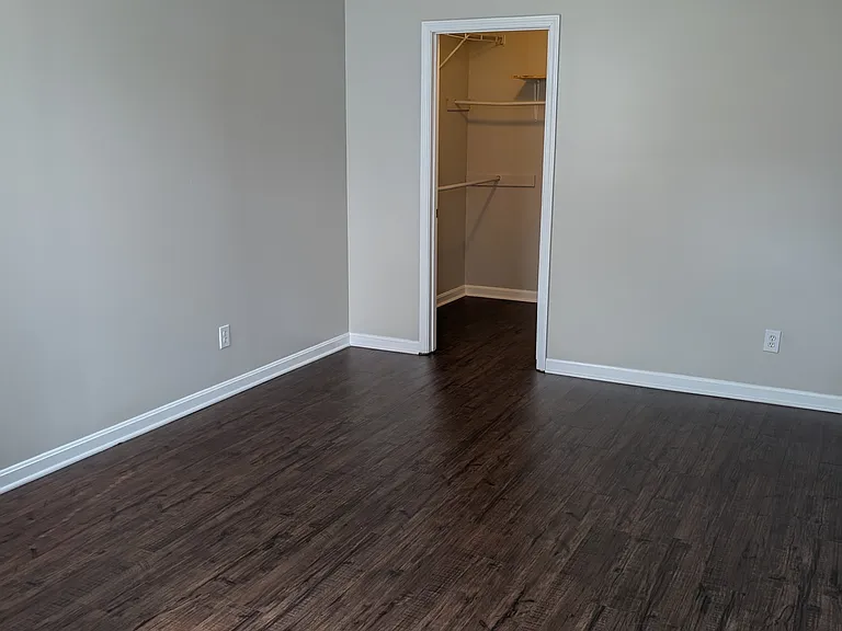 Spacious primary bedroom featuring new luxury vinyl flooring, ceiling fan, and walk-in closet