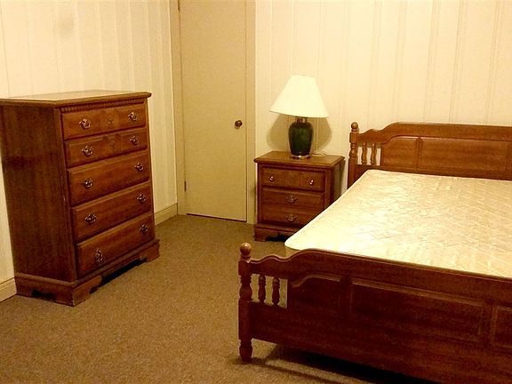 Bedroom with full-sized bed, 2 dressers and side table.