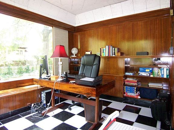 Sunny office off living room has built-in cabinetry and window seats