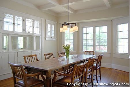 Fabulous formal dining room with oversized casement window, coffered ceiling, chandelier, decorative fireplace and builtin china buffet.