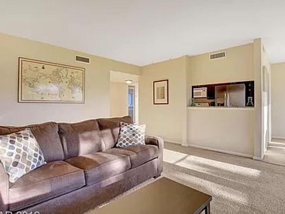 Living room with a view of the Strip and golf course. Incudes sleeper sofa, tv with a stand, WiFi router, coffee table, lamp, picture on the wall, decorative pillows