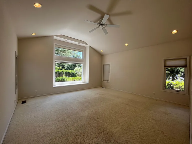 Large primary suite features high vaulted ceiling and a large picture window boasting the view of the lush garden.