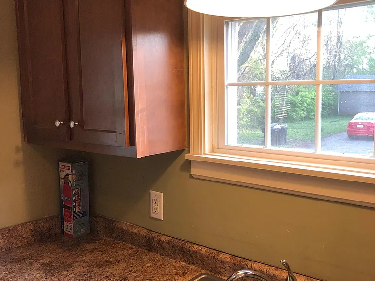 Kitchen sink looks out on parking area and back yard