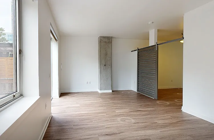 Apartment living room with wood-style flooring and large windows.