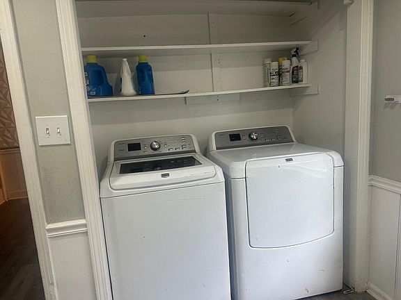 Dedicated laundry nook with full-size washer and dryer plus built-in shelving for detergents and household storage.
