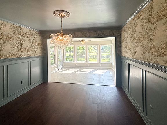 Dining Room & Sunroom
This home features a stylish dining room with rich wood floors, custom wainscoting, and elegant wallpaper detail, paired with a statement chandelier. The space opens into a bright sunroom.