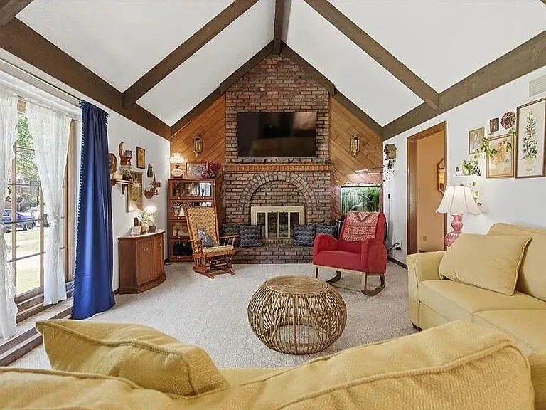 Beautiful central living room designed for conversation and comfort, highlighted by a dramatic brick fireplace and elegant architectural beams.