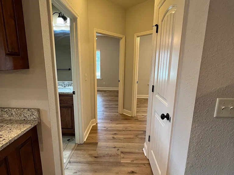 Hallway with storage closet leading to second bath and additional bedrooms.