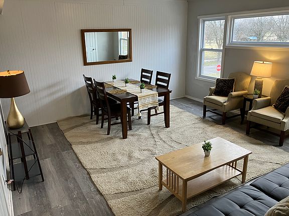 Bright living space with sofa, two armchairs, and full dining table _ ideal for hosting or unwinding after work.
