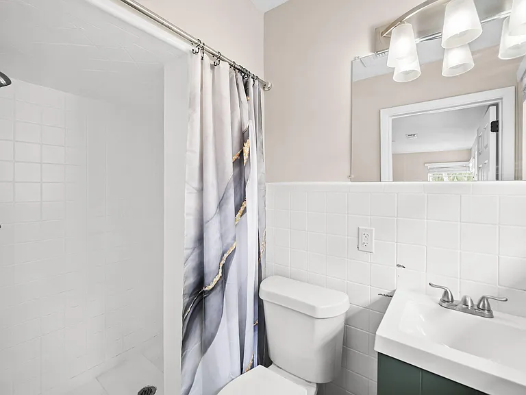 Clean full bathroom with tiled shower/tub, single-sink vanity, and large mirror with overhead lighting for easy routines.