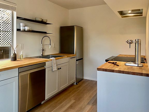 Renovated kitchen with stainless appliances, induction range, and wood countertops.