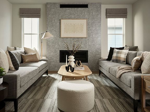 A cozy and inviting living room with plush gray sofas, a wooden coffee table, and a fireplace with a