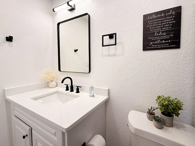 Bathroom with a clean vanity, matte-black fixtures, framed mirror, and convenient countertop space for daily essentials.
