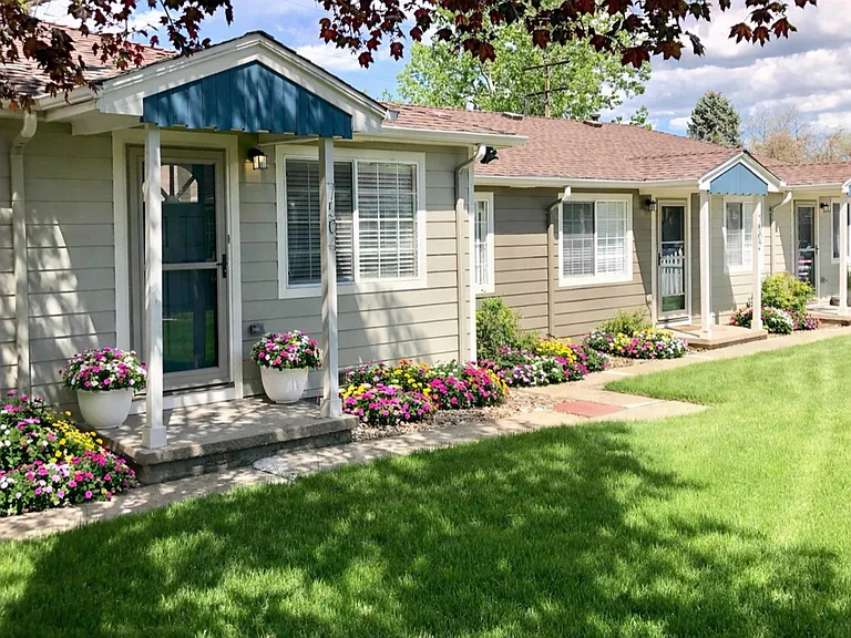 Charming cottage-style residences surrounded by lush green lawns and vibrant landscaping.