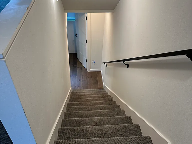 Carpeted stairway from kitchen to upper floor.