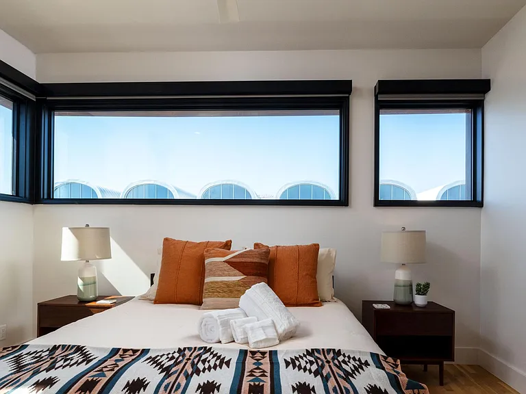 Bedroom 2 features a queen bed and windows on two sides, with room-darkening shades for restful sleep and added privacy.