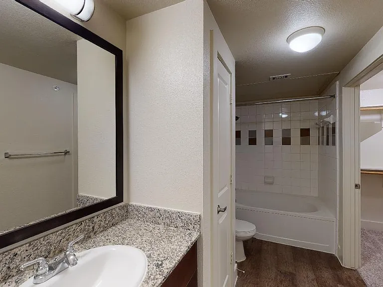 Apartment bathroom with large soaking tub and wood-style flooring.