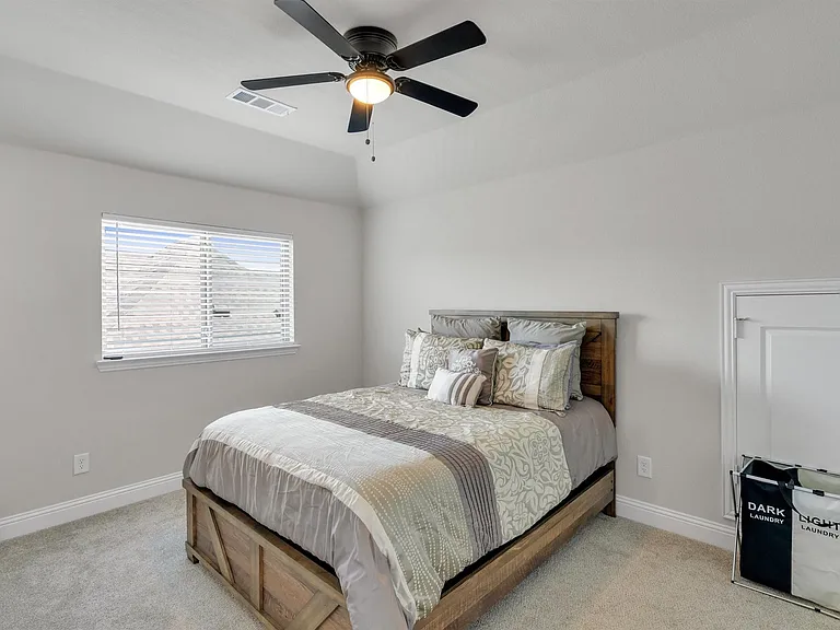 Carpeted room featuring a ceiling fan with integrated lighting, a window with horizontal blinds, a single door with a knob, and white baseboards