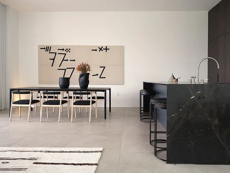 Minimalist Dining Space with Architectural Details _ Designed for both form and function, this dining area features high ceilings, sculptural lighting, and seamless transitions to the kitchen and living areas, embodying the refined elegance of Asteras.
